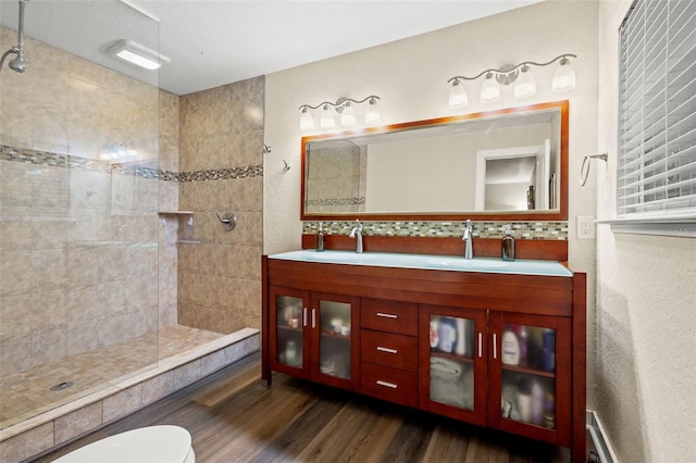 bathroom featuring vanity, hardwood / wood-style flooring, decorative backsplash, toilet, and tiled shower