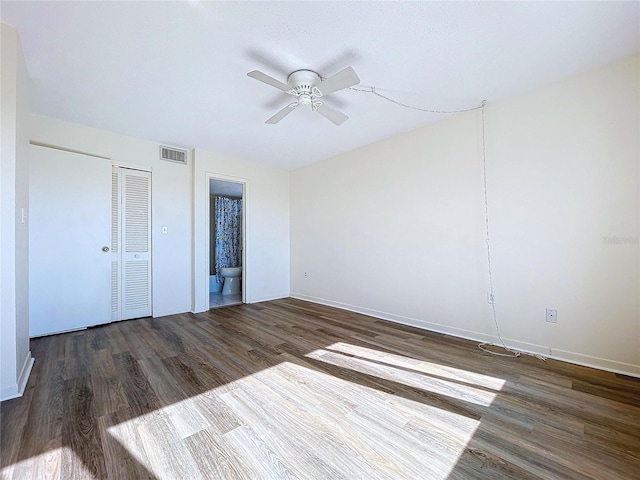 unfurnished bedroom with ceiling fan, a closet, ensuite bathroom, and dark hardwood / wood-style floors