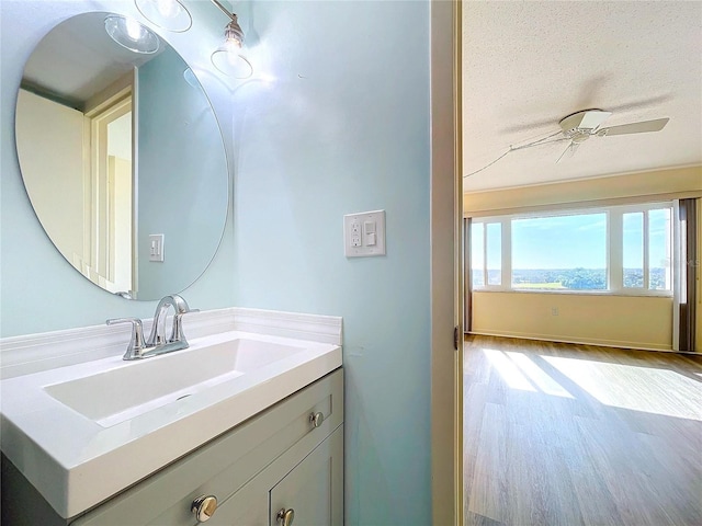 bathroom with ceiling fan, hardwood / wood-style floors, vanity, and a textured ceiling