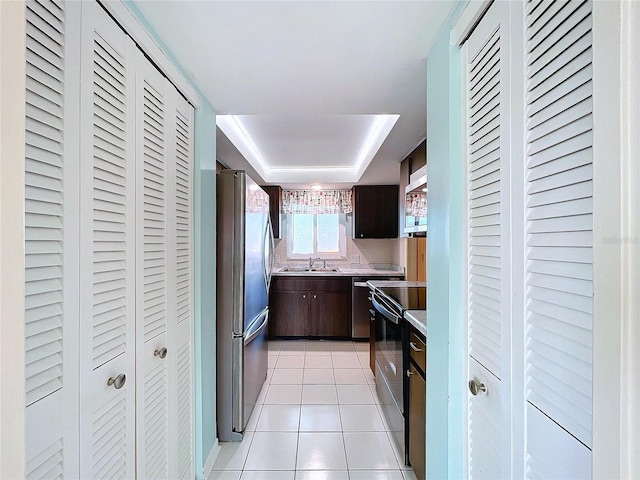 kitchen with appliances with stainless steel finishes, sink, dark brown cabinets, and light tile patterned flooring