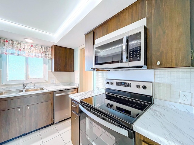 kitchen with decorative backsplash, sink, light tile patterned floors, and stainless steel appliances