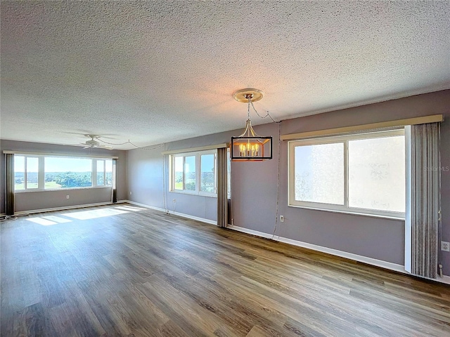 spare room with ceiling fan with notable chandelier, wood-type flooring, and a textured ceiling