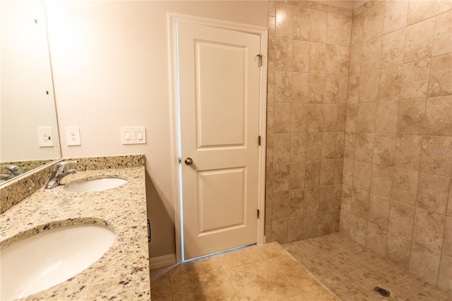 bathroom with tile patterned flooring, a tile shower, and vanity