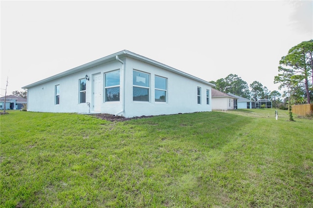447 Reading St, Lehigh Acres, FL 33974 - rear view of house featuring stucco siding and a lawn