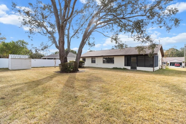 rear view of house with a lawn and a storage shed