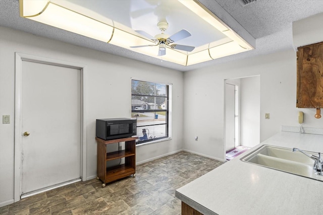 kitchen with a textured ceiling, ceiling fan, and sink