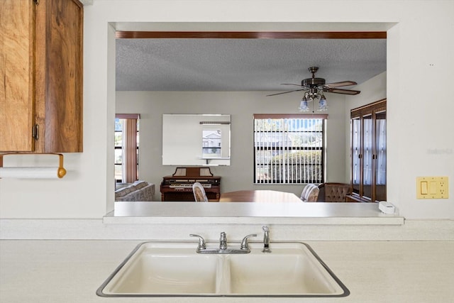 kitchen with a textured ceiling, ceiling fan, and sink