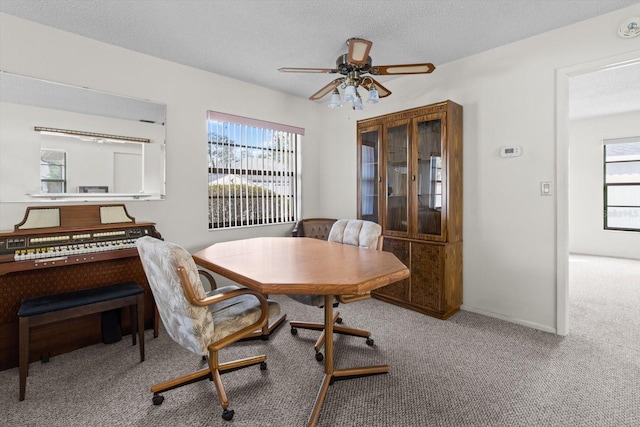 dining room with carpet flooring, a textured ceiling, ceiling fan, and a healthy amount of sunlight