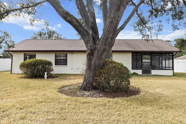 rear view of house with a lawn and a sunroom