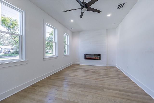 unfurnished living room with light wood finished floors, a fireplace, visible vents, and a healthy amount of sunlight