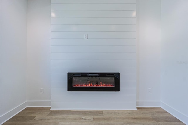 room details with a large fireplace, wood finished floors, and baseboards