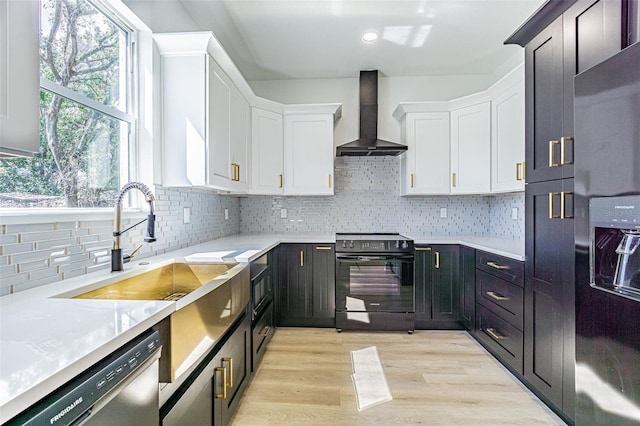 kitchen featuring dishwashing machine, wall chimney exhaust hood, fridge with ice dispenser, black electric range, and white cabinetry