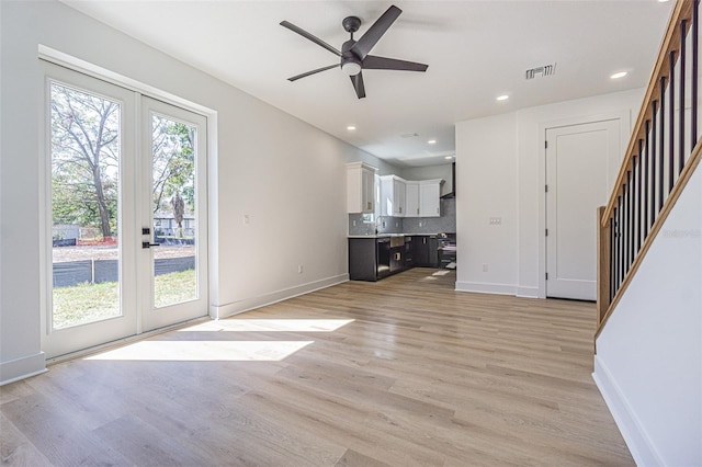 unfurnished living room with plenty of natural light, stairs, visible vents, and french doors