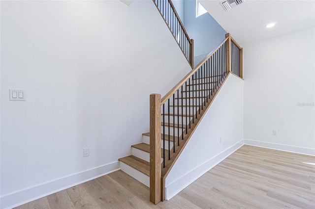 stairs featuring recessed lighting, a high ceiling, wood finished floors, visible vents, and baseboards