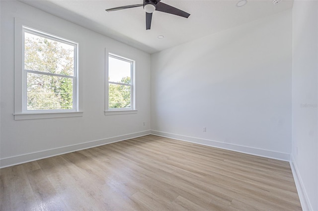 spare room featuring a ceiling fan, light wood-style flooring, and baseboards