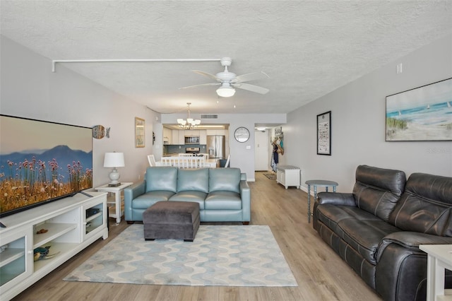 living room with ceiling fan with notable chandelier, a textured ceiling, and light hardwood / wood-style floors