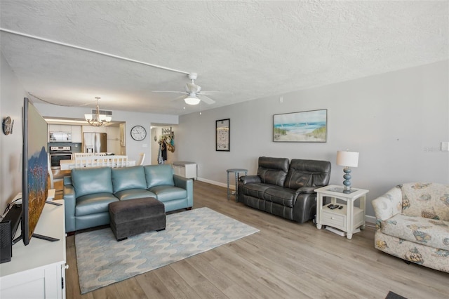 living room featuring a textured ceiling, light hardwood / wood-style flooring, and ceiling fan with notable chandelier