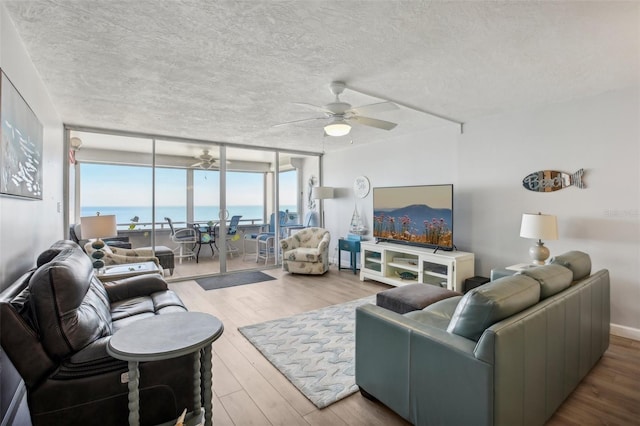 living room featuring floor to ceiling windows, ceiling fan, wood-type flooring, and a textured ceiling