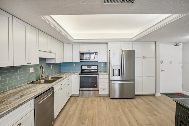 kitchen featuring white cabinets, a raised ceiling, sink, light wood-type flooring, and stainless steel appliances