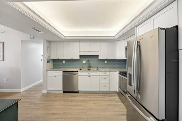 kitchen with appliances with stainless steel finishes, light hardwood / wood-style flooring, white cabinetry, and sink