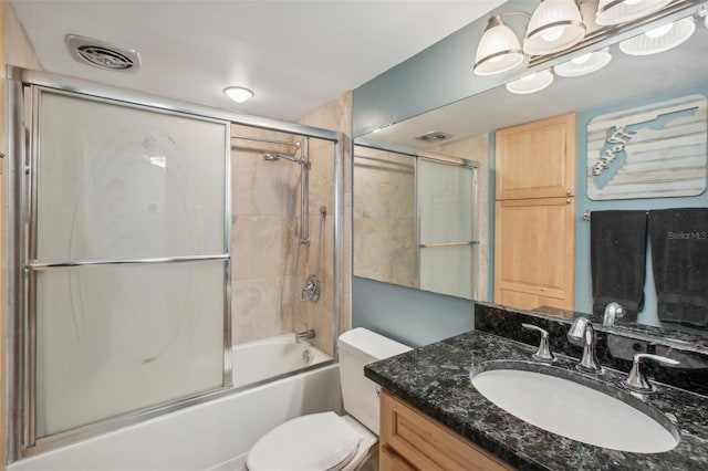 full bathroom featuring combined bath / shower with glass door, vanity, and toilet