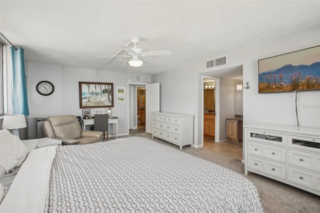 bedroom featuring light carpet, a textured ceiling, connected bathroom, and ceiling fan