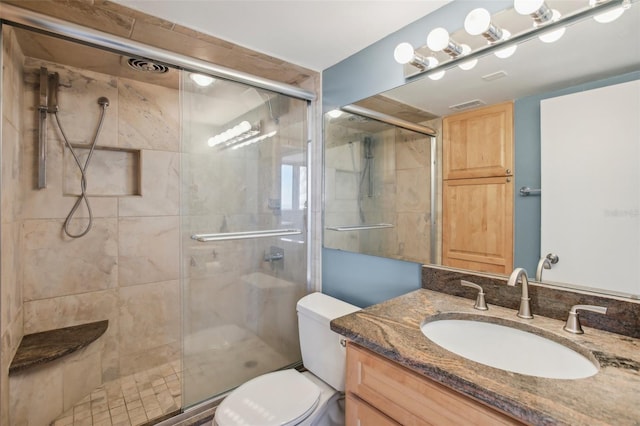 bathroom with vanity, a shower with shower door, and toilet