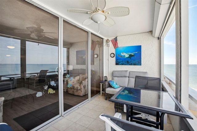 sunroom featuring ceiling fan and a water view