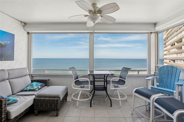 sunroom with ceiling fan and a water view