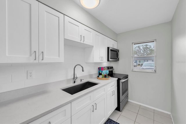 kitchen with white cabinets, stainless steel appliances, decorative backsplash, sink, and light tile patterned floors