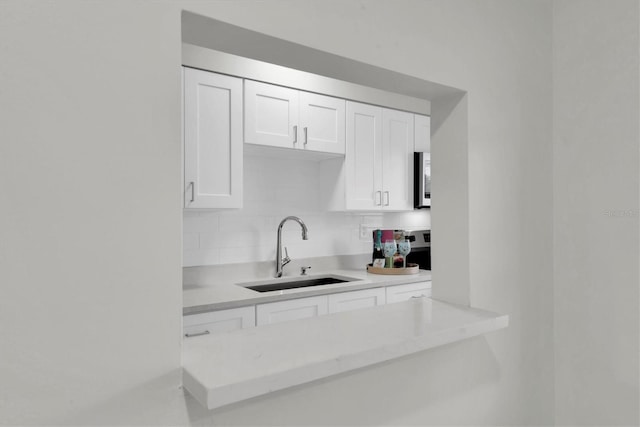 kitchen with white cabinetry, tasteful backsplash, and sink