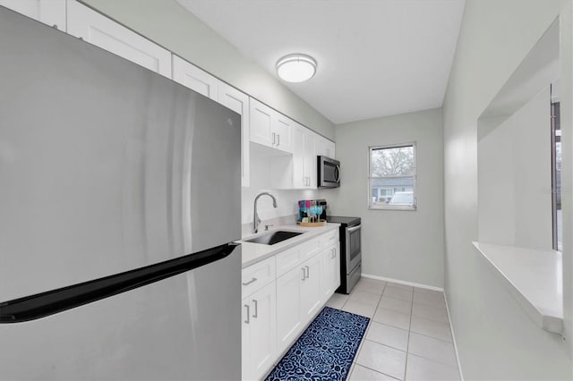 kitchen with white cabinets, appliances with stainless steel finishes, sink, and light tile patterned floors