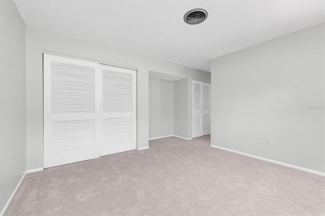 unfurnished bedroom with light colored carpet and a closet