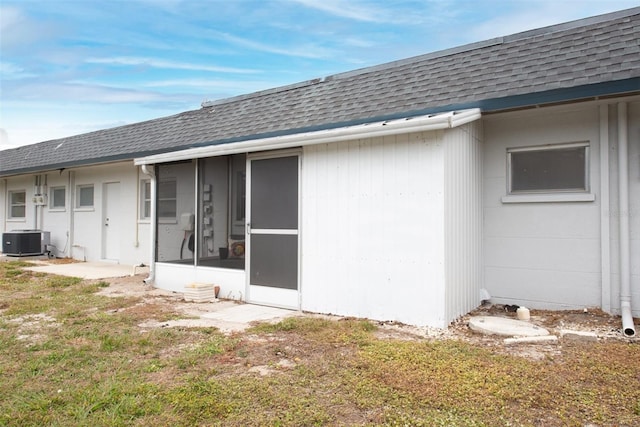 rear view of house featuring a sunroom, cooling unit, and a lawn