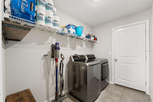 laundry area featuring light tile patterned floors, a textured ceiling, and washing machine and clothes dryer