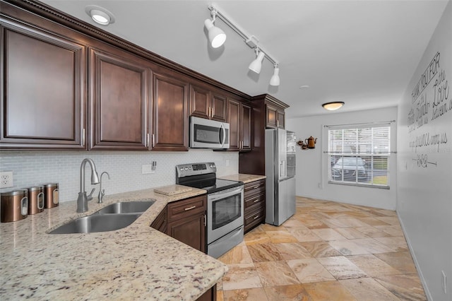 kitchen with rail lighting, sink, light stone countertops, appliances with stainless steel finishes, and dark brown cabinets