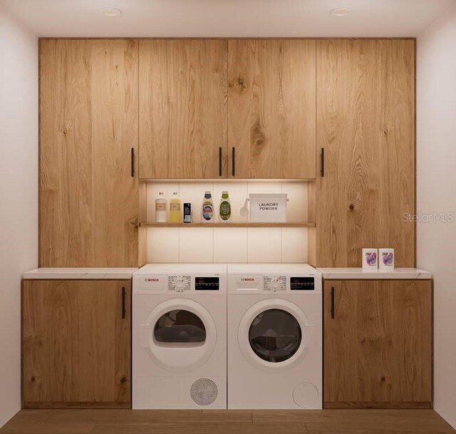 laundry room featuring cabinets, light hardwood / wood-style flooring, and washing machine and clothes dryer