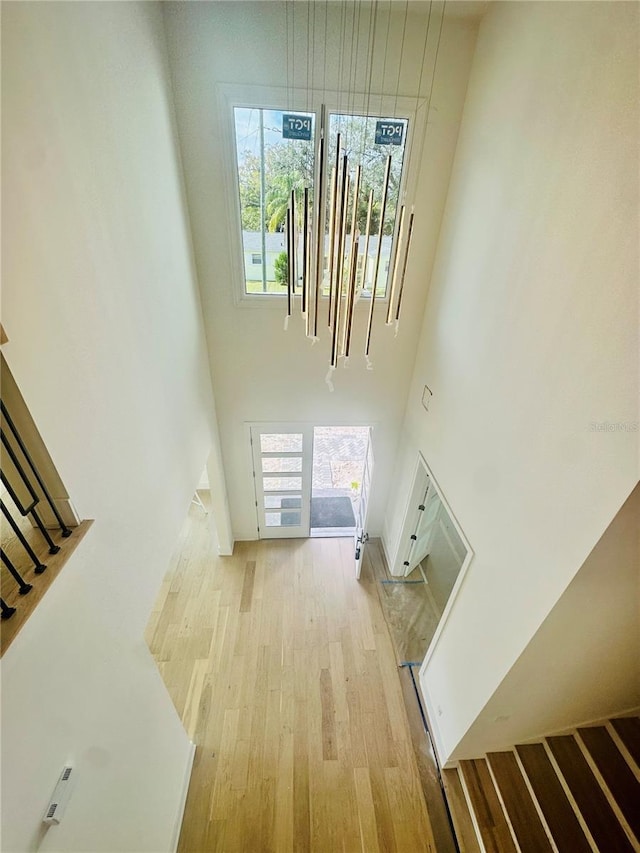 unfurnished living room featuring light wood-type flooring and a towering ceiling