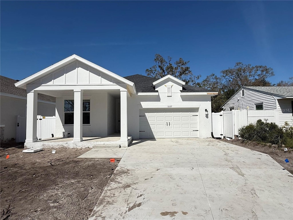 view of front facade featuring driveway, an attached garage, board and batten siding, and stucco siding