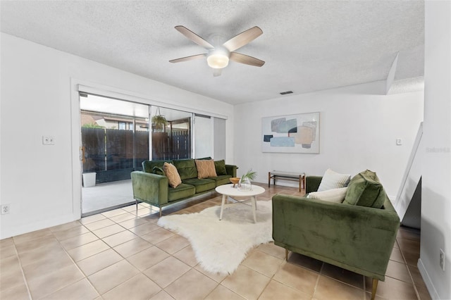 living room with ceiling fan, light tile patterned floors, and a textured ceiling