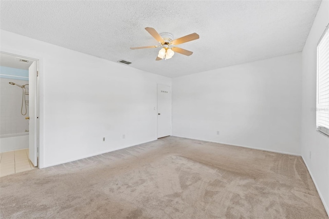 carpeted spare room featuring ceiling fan and a textured ceiling