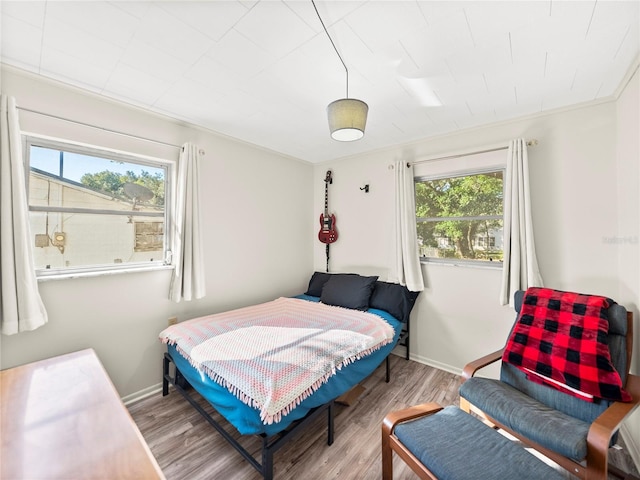 bedroom featuring multiple windows, hardwood / wood-style floors, and ornamental molding