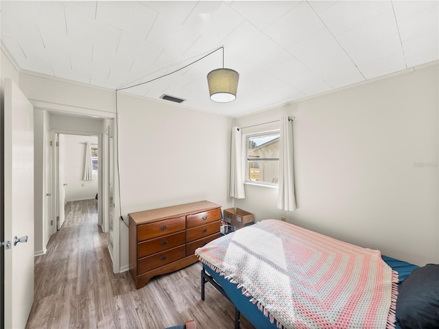 bedroom with crown molding and light hardwood / wood-style flooring