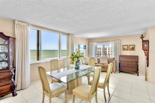 tiled dining room with a textured ceiling and a water view