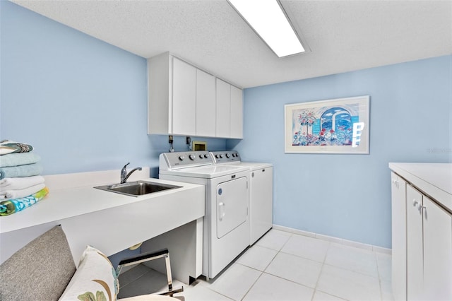 clothes washing area featuring cabinets, a textured ceiling, sink, light tile patterned floors, and washing machine and clothes dryer