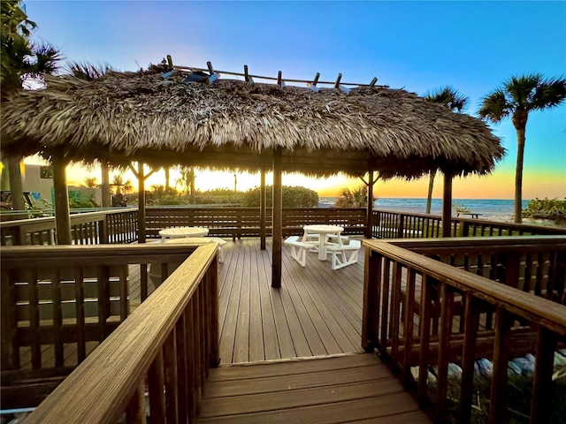 dock area with a deck with water view, a gazebo, and a beach view