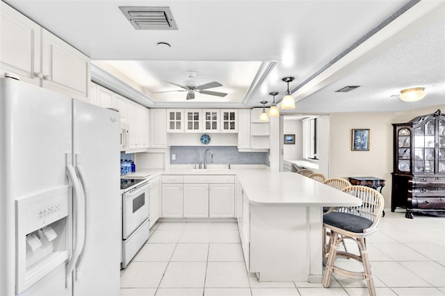 kitchen featuring a breakfast bar, white appliances, white cabinets, decorative light fixtures, and kitchen peninsula