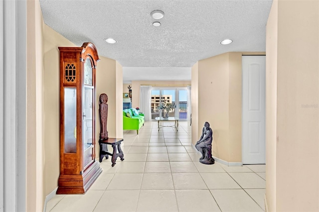 hall featuring light tile patterned floors and a textured ceiling