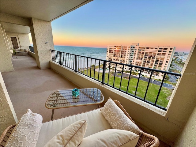 balcony at dusk featuring a water view