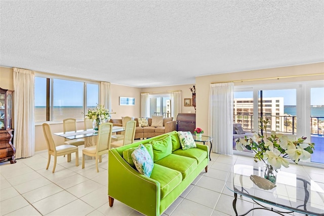 tiled living room featuring a textured ceiling and a water view